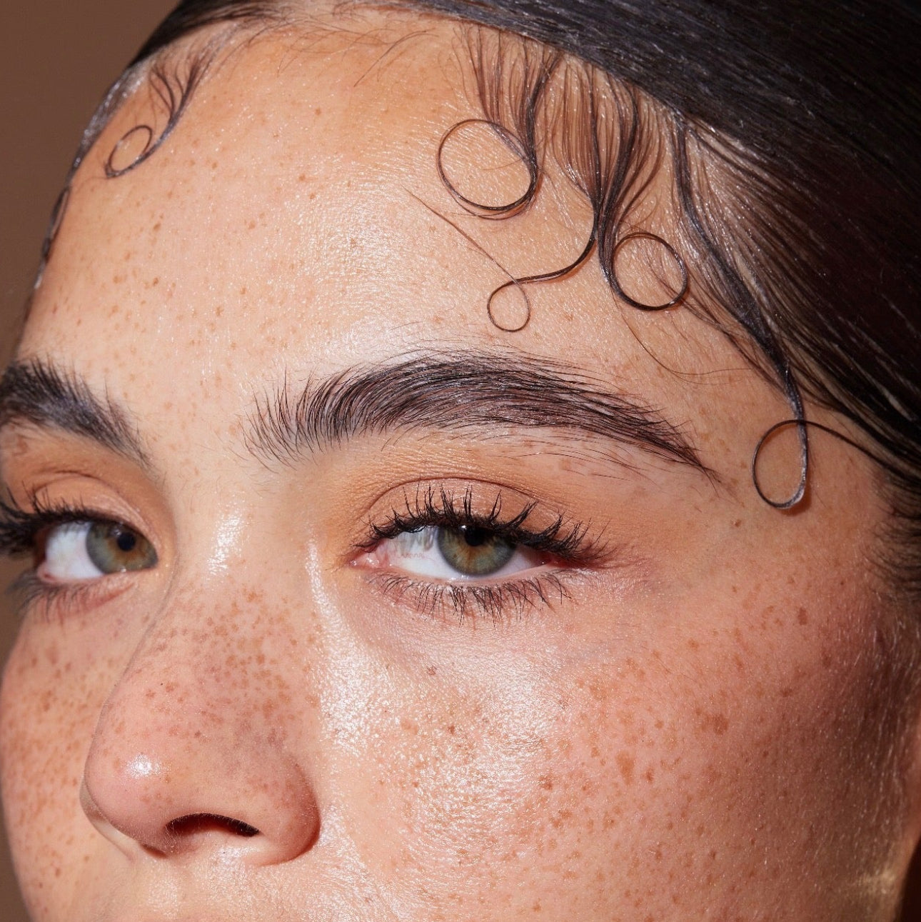 Close-up of a person's face with freckles and detailed eyebrow design.